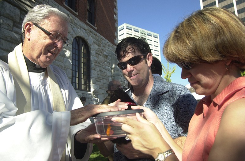 Father Sam Payne, left, blesses John and Kelly Coffelt's goldfish during the annual Blessing of the Animals service in front of St. Paul's Episcopal Church on Sunday. / Staff Photo by Leigh Shelle Hunt