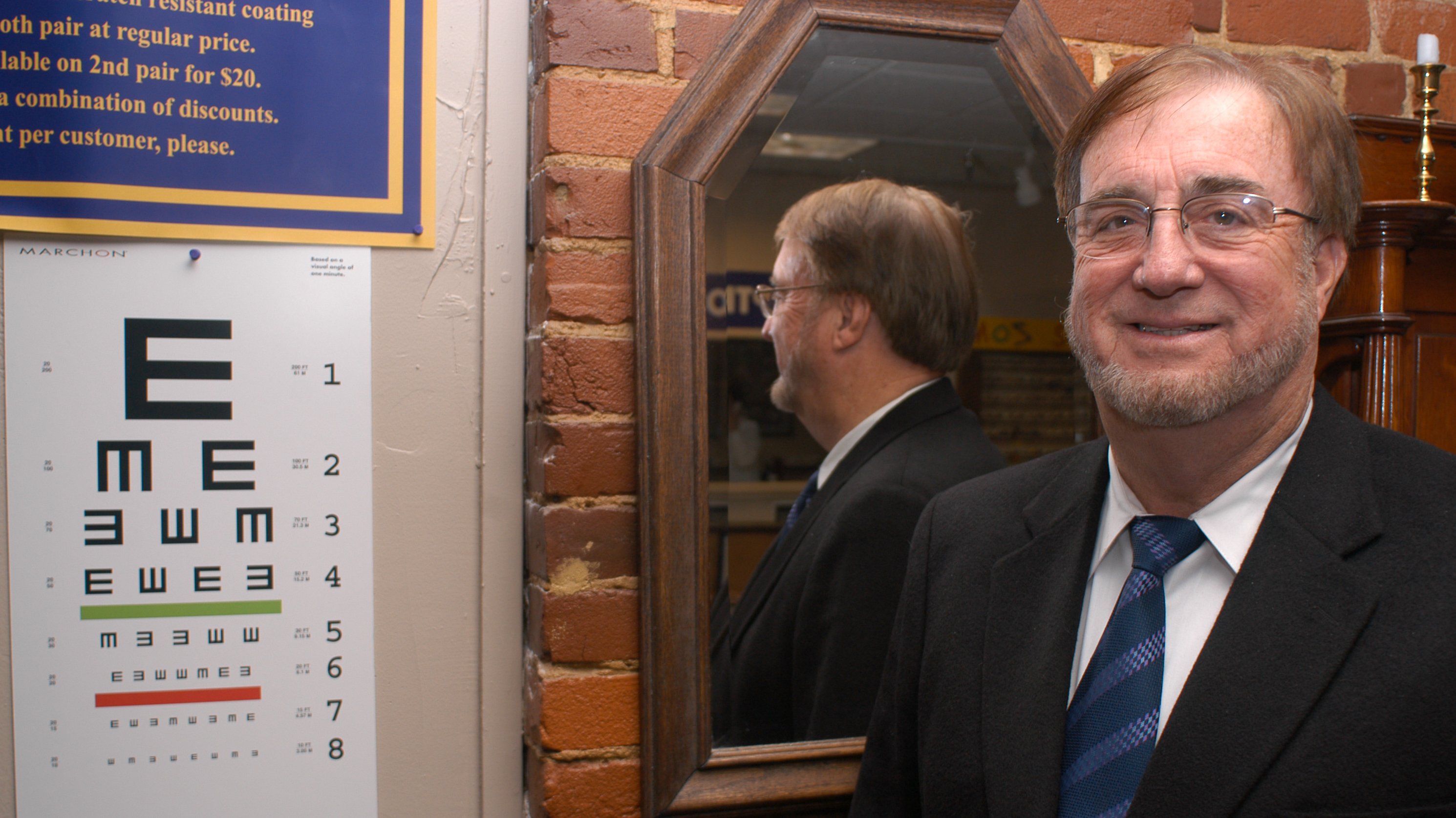 Jim Crittenden stands in front of an eye chart at the Eyear store on 10th and Market. Mr. Crittenden was one of the purchasers of the building. / Staff photo by Dan McLaughlin