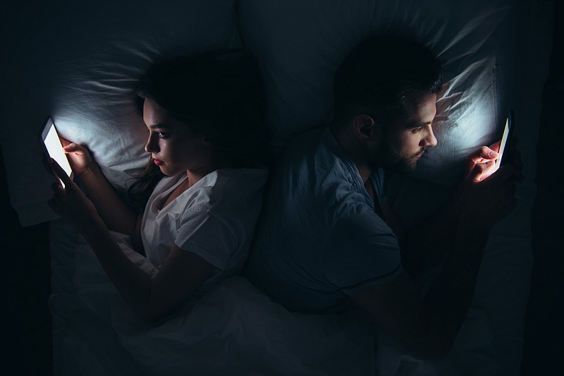 Couple lying back to back in bed and using smartphones at night. / Photo by Getty Images/iStockphoto/LightFieldStudios