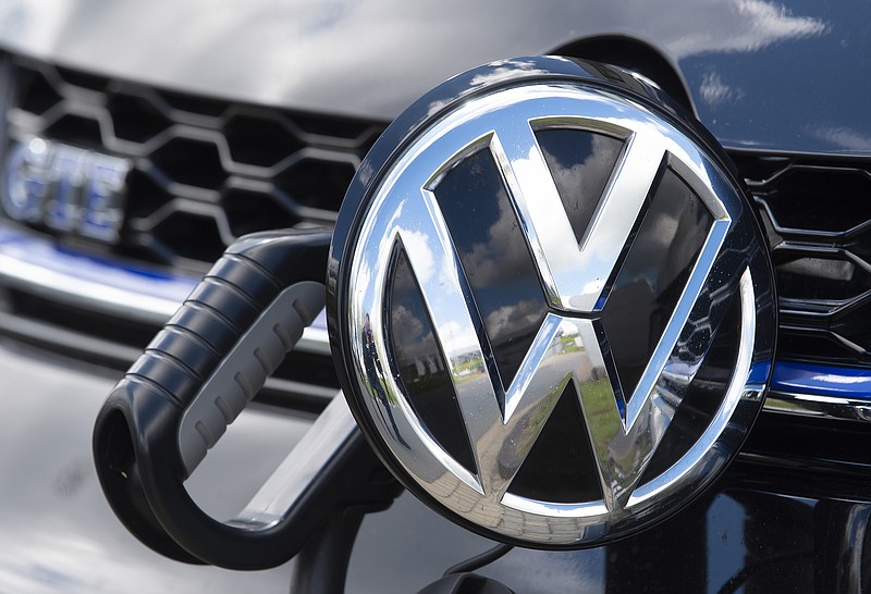 In this Tuesday, May 14, 2019 photo, an e-Golf car is fixed with a charging station during a press tour at the plant of the German manufacturer Volkswagen AG (VW) in Zwickau, Germany. Automaker Volkswagen is raising the bar for its plunge into battery powered cars, saying it will reach its goal of 1 million e-autos per year two years earlier than planned. (AP Photo/Jens Meyer)