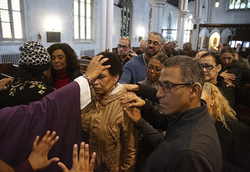 In this Sunday, Dec. 15, 2019, photo, the Rev. Luis Barrios, left, places his hand on the head of Mercedes Katrocino, center, a deaf congregant, as he and the rest of the congregation pray for Katrocino's health and failing eyesight at Holyrood Episcopal Church in New York on Sunday, Dec. 15, 2019. (AP Photo/Jessie Wardarski)