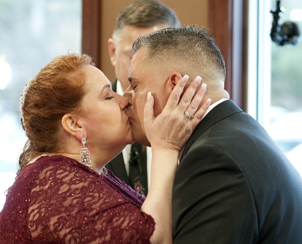 Newlyweds Valerie Sneade and Jason Roy kiss during their wedding ceremony at the Dunkin' Donuts on Friday, Dec. 27, 2019 in Worcester, Mass. The couple reunited for their wedding vows at the Dunkin' Donuts where their young love splintered nearly thirty years ago. Except for a couple of chance encounters, Sneade and Roy mostly didn't see each other for 25 years after a conversation about their future at the same donut shop in 1992 led the young couple to slowly cut ties. Sneade and Roy blame misunderstandings at the time and words that didn't come out right. (Rick Cinclair/Worcester Telegram & Gazette via AP)