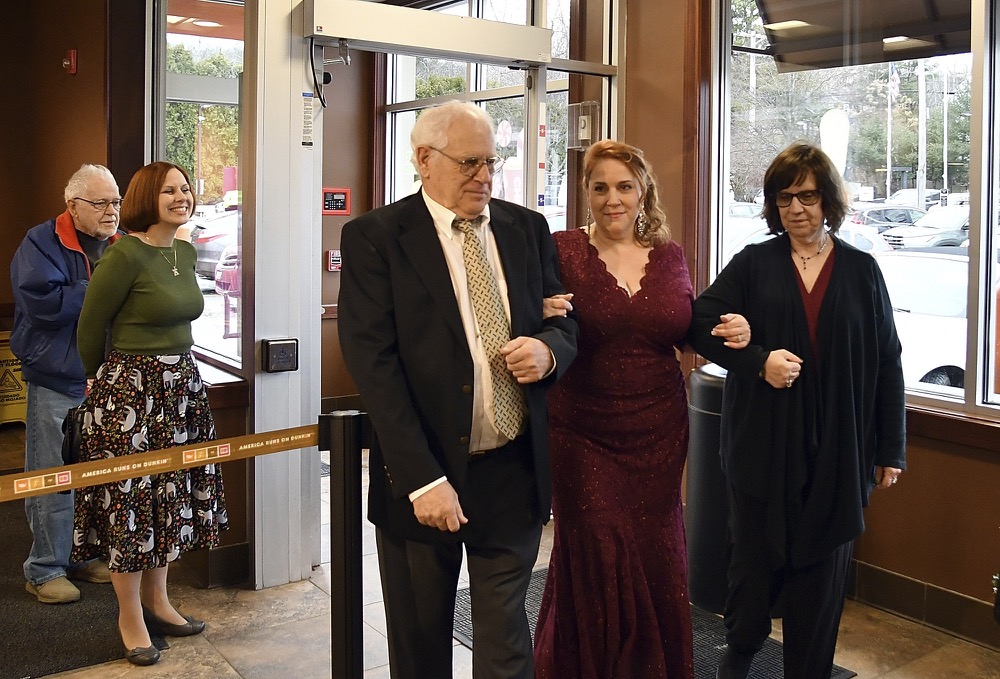 Bride Valerie Sneade walks down the aisle by her parents Richard Sneade and Eileen Harper at the Dunkin' Donuts on Friday, Dec. 27, 2019 in Worcester, Mass. The couple reunited for their wedding vows at the Dunkin' Donuts where their young love splintered nearly thirty years ago. Except for a couple of chance encounters, Sneade and Roy mostly didn't see each other for 25 years after a conversation about their future at the same donut shop in 1992 led the young couple to slowly cut ties. Sneade and Roy blame misunderstandings at the time and words that didn't come out right. (Rick Cinclair/Worcester Telegram & Gazette via AP)