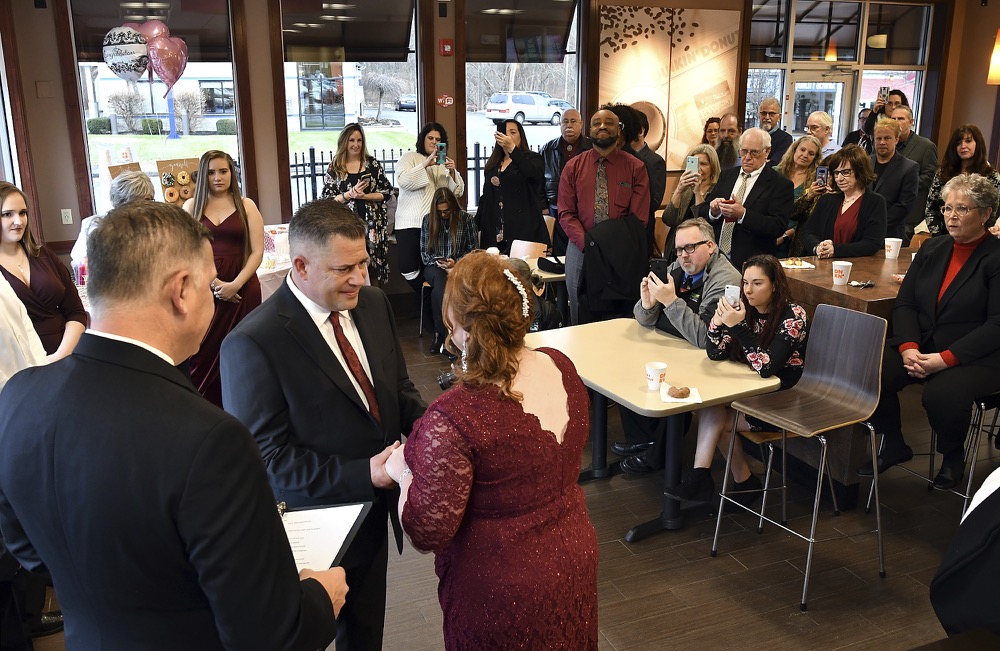 Jason Roy and Valerie Sneade say their vows in front of friends and family at the Dunkin' Donuts on Friday, Dec. 27, 2019 in Worcester, Mass. The couple reunited for their wedding vows at the Dunkin' Donuts where their young love splintered nearly thirty years ago. Except for a couple of chance encounters, Sneade and Roy mostly didn't see each other for 25 years after a conversation about their future at the same donut shop in 1992 led the young couple to slowly cut ties. Sneade and Roy blame misunderstandings at the time and words that didn't come out right. (Rick Cinclair/Worcester Telegram & Gazette via AP)