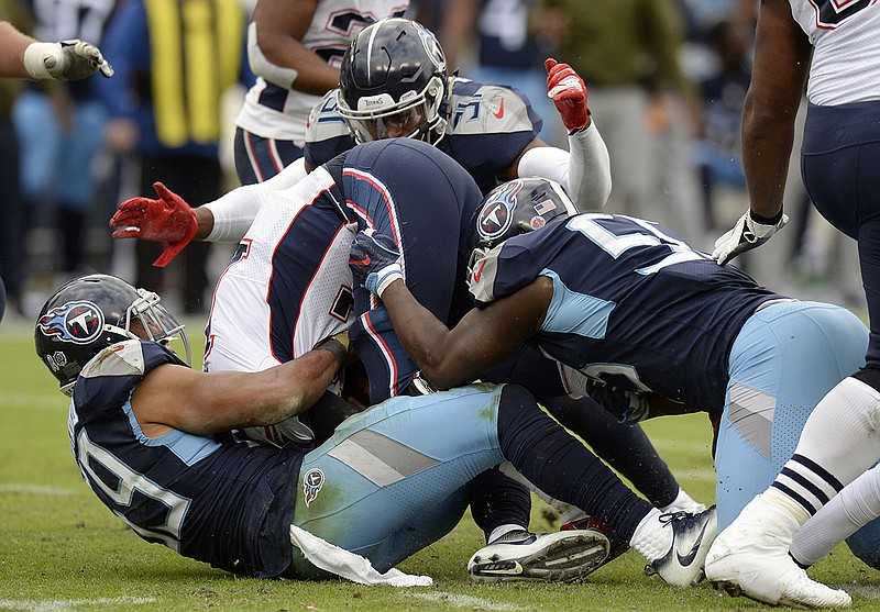 New England Patriots quarterback Tom Brady, center, is folded up and sacked by a group of Tennessee Titans in the second half on Nov. 11, 2018, in Nashville. The Titans stunned the Patriots by winning 34-10, and now the teams will meet for the first time since then by squaring off in the first round of the AFC playoffs next weekend. / AP photo by Mark Zaleski