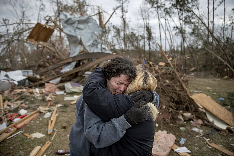 FILE - In this March 4, 2019 file photo, Carol Dean, left, cries while embraced by Lawanda Anderson as Dean sifts through the debris of the home she shared with her husband, David Wayne Dean, who died when a tornado destroyed the house in Beauregard, Ala. This was one of the top stories in Alabama in 2019  .(AP Photo/David Goldman, File)