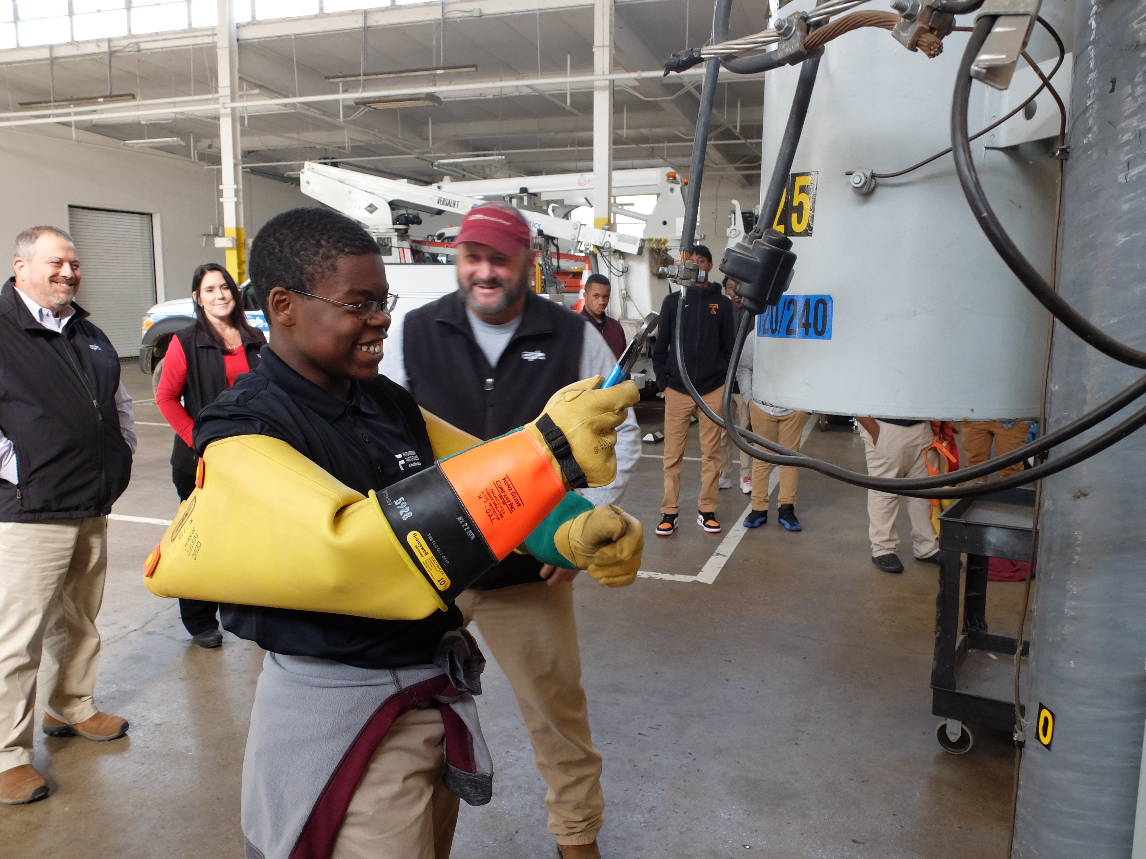 Staff photo by Tim Barber/ Deshawn Bass attempts to loosen a nut with pliers while wearing rubber insulated sleeves as Steve Raulston reacts, center, Tuesday, Nov. 26, 2019, during Tyner's Future Ready Institute tour of the Electric Power Board's Operations Center 2.