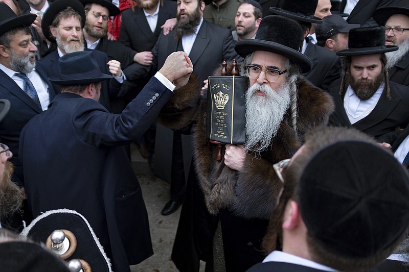 Community members including Rabbi Chaim Rottenberg, right center, celebrate the arrival of a new Torah near the rabbi's residence in Sunday, Dec. 29, 2019, following a stabbing Saturday night during a Hanukkah celebration Monsey, N.Y. A knife-wielding man stormed into the home and stabbed five people as they celebrated Hanukkah in an Orthodox Jewish community north of New York City, an ambush the governor said Sunday was an act of domestic terrorism fueled by intolerance and a "cancer" of growing hatred in America. (AP Photo/Craig Ruttle)