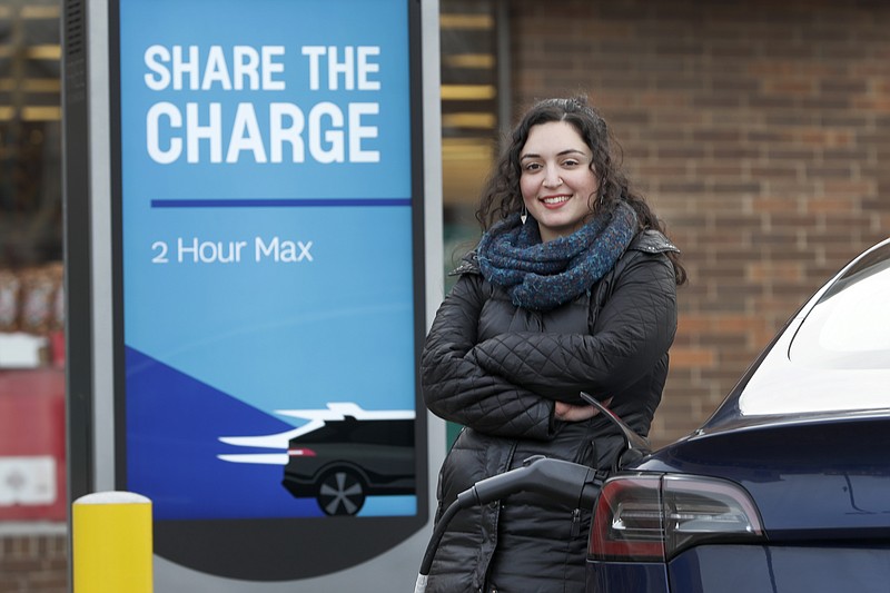 In this Friday, Dec. 20, 2019, photo, Neda Deylami poses for a portrait while charging her electric vehicle at a Chicago area grocery store. Owners of electric vehicles in a number of states will start seeing fees to pay for road repairs in the new year. At least eight states will begin charging new or higher registration fees Wednesday, Dec. 25, for electric vehicles or plug-in hybrids. "It's kind of a blanket penalty for anyone who chooses to go electric," said Deylami, a Tesla owner who founded Chicago for EVs, a group that advocates for electric vehicles. (AP Photo/Charles Rex Arbogast)