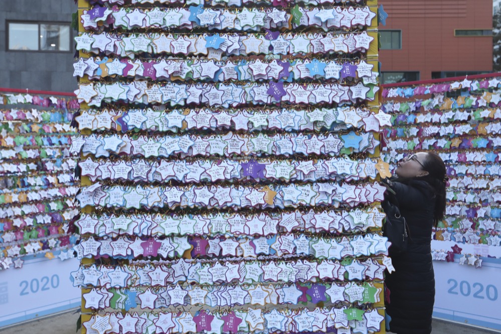 A woman hangs a paper note bearing her New Year wishes to a wire at Jogyesa Buddhist temple in Seoul, South Korea, Tuesday, Dec. 31, 2019. (AP Photo/Ahn Young-joon)