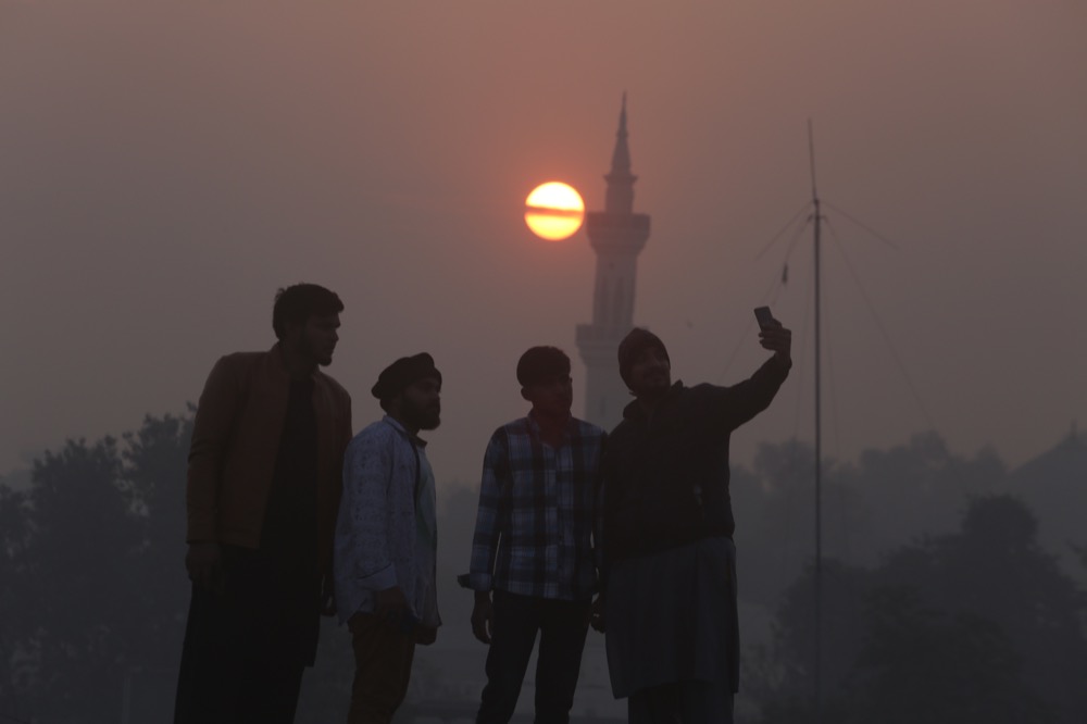 People take a selfie during the last sunset of 2019, in Peshawar, Pakistan, Tuesday, Dec. 31, 2019. (AP Photo/Muhammad Sajjad)