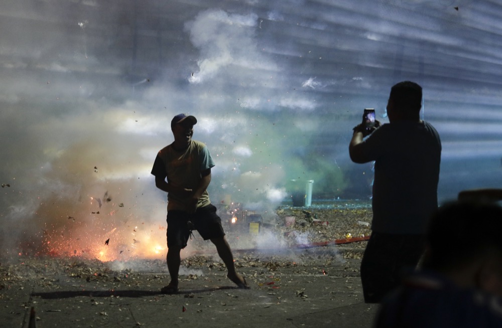 A Filipino poses for a selfie beside exploding firecrackers as they celebrate the coming of the New Year early Wednesday, Jan. 1, 2020 in Manila, Philippines. Filipinos welcome the New Year with noise and firecrackers in the belief that this will drive away bad spirits and bring in good luck. (AP Photo/Aaron Favila)