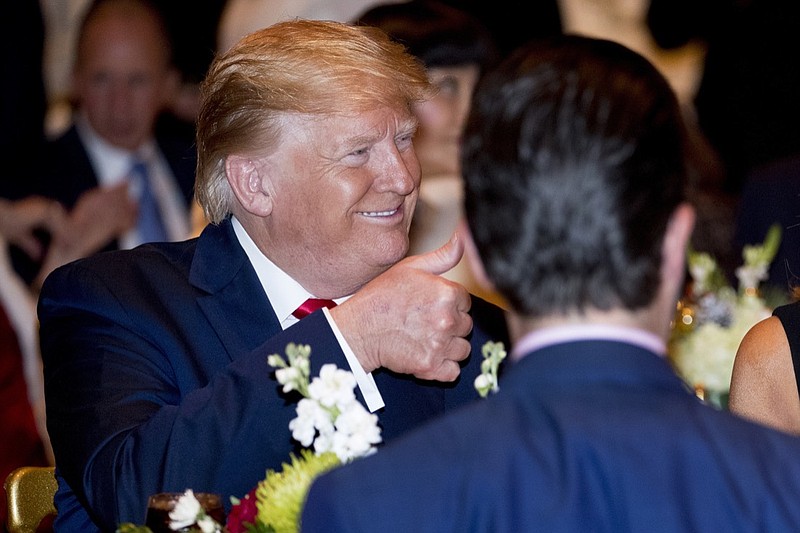 President Donald Trump gives a thumbs-up after arriving for Christmas Eve dinner at Mar-a-lago in Palm Beach, Fla., Tuesday, Dec. 24, 2019. Donald Trump Jr., the son of President Donald Trump, is pictured in foreground. (AP Photo/Andrew Harnik)