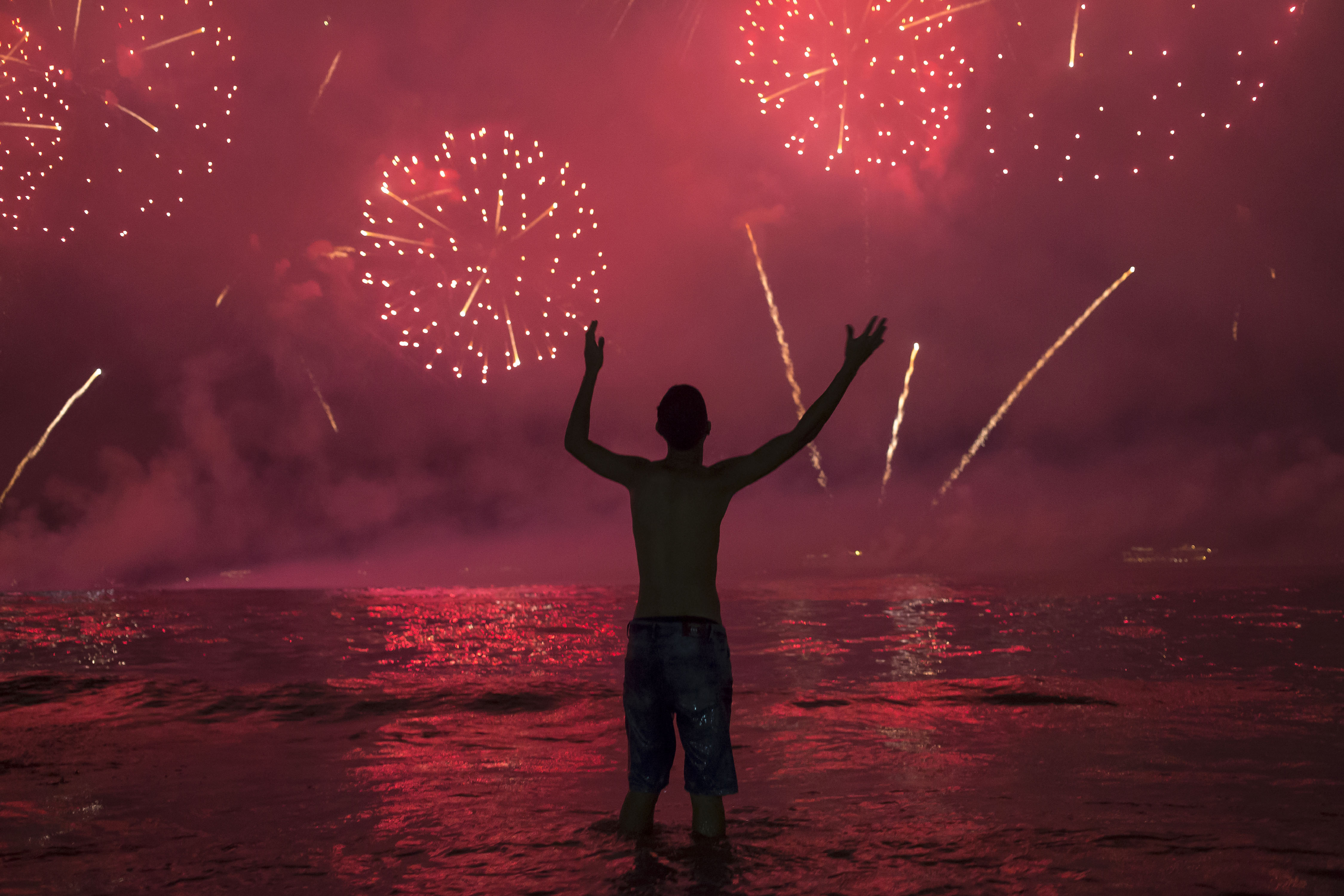 A man watches fireworks exploding over Copacabana Beach during the New Year's celebrations, in Rio de Janeiro, Brazil, Wednesday, Jan. 1, 2020. (AP Photo/Bruna Prado)