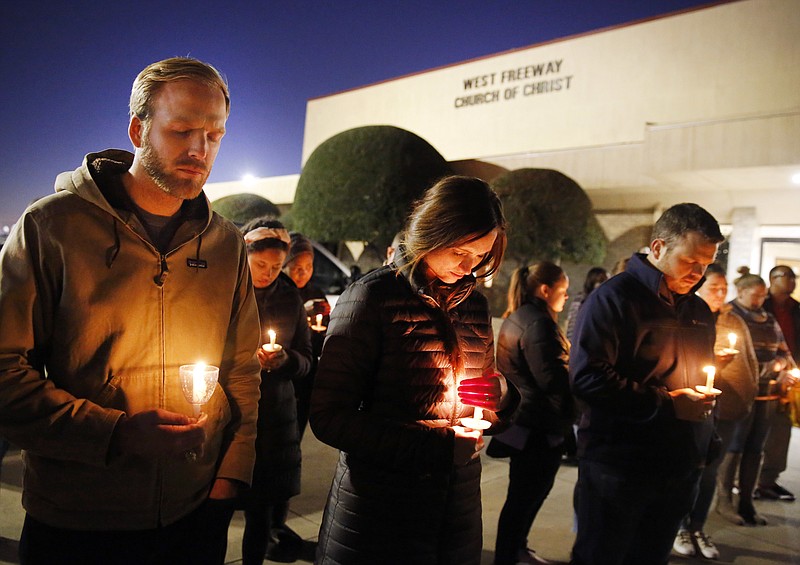 Church and community members, including Matt Pacholczyk, left, and his wife, Faith Pacholczyk, stand outside West Freeway Church of Christ for a candlelight vigil, Monday, Dec. 30, 2019, in White Settlement, Texas. A gunman shot and killed two people before an armed security officer returned fire, killing him during a service at the church on Sunday. (Tom Fox/The Dallas Morning News via AP)