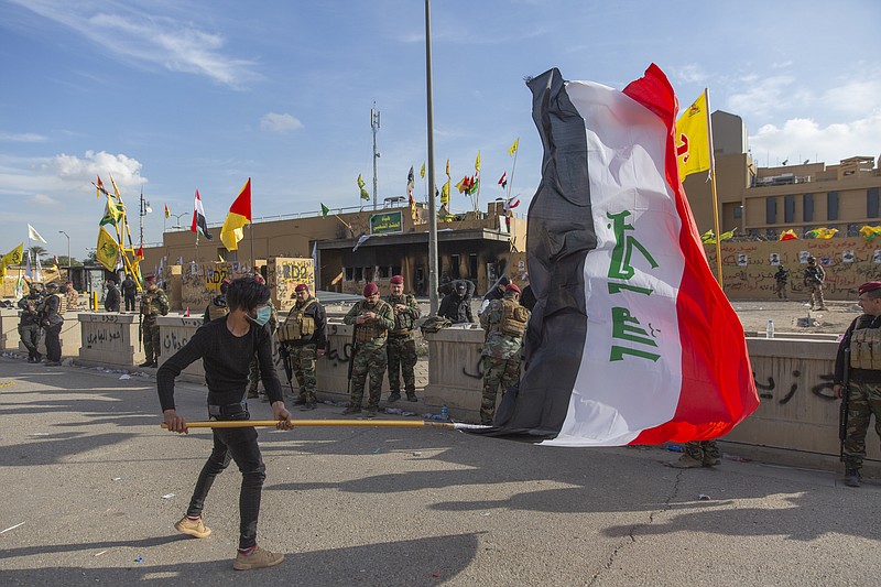 The Associated Press / A man waves the Iraqi flag while Iraqi army soldiers guard the front of the U.S. Embassy in Baghdad, Iraq, Wednesday.