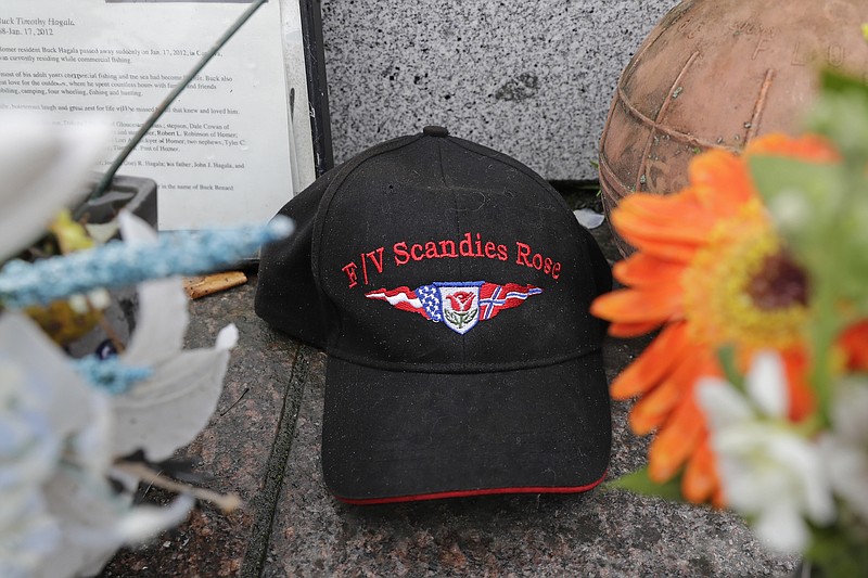 A ball cap with the name of the crab fishing boat Scandies Rose rests at the Seattle Fishermen's Memorial, Thursday, Jan. 2, 2020, in Seattle. The search for five crew members of the Scandies Rose in Alaska has been suspended, the U.S. Coast Guard said after two other crew members of the vessel were rescued after the 130-foot crab fishing boat from Dutch Harbor, Alaska, sank on New Year's Eve. (AP Photo/Ted S. Warren)