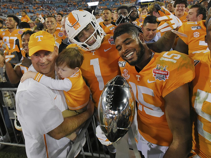 Tennessee football coach Jeremy Pruitt holds his son Flynt as he poses with players, including wide receivers Marquez Callaway (1) and Jauan Jennings (15,) after the team's 23-22 win over Indiana in the TaxSlayer Gator Bowl on Thursday night in Jacksonville, Fla. / AP photo by Bob Self