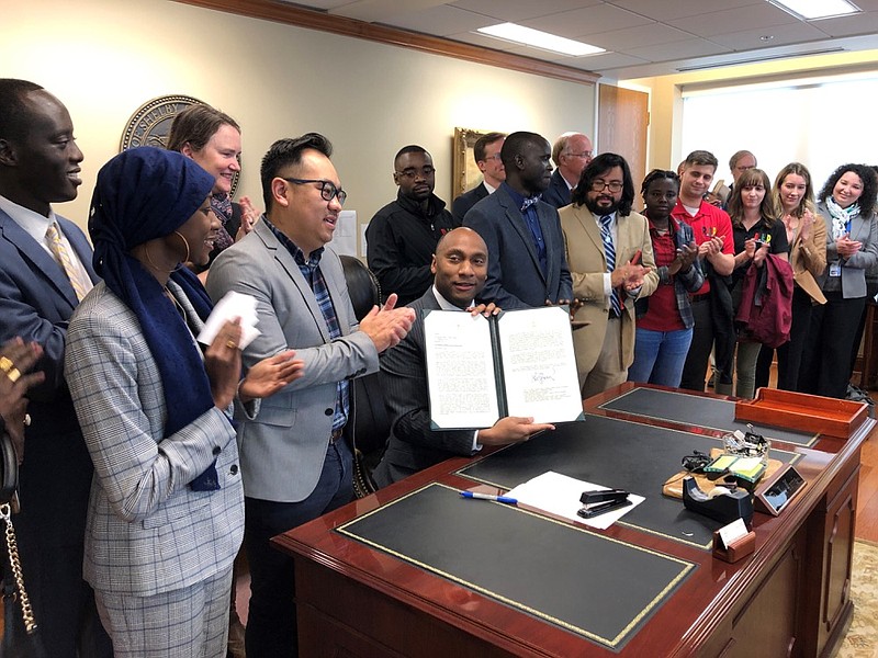 Shelby County, Tenn., Mayor Lee Harris, seated at desk, holds up a letter reaffirming Tennessee's largest county's commitment to keep resettling refugees on Friday, Jan. 3, 2020, in Memphis, Tenn. (AP Photo/Adrian Sainz)


