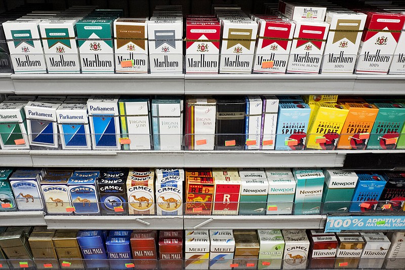 FILE - This Aug. 28, 2017 file photo shows cigarettes displayed on a store shelf in New York. With a new law enacted in December 2019, anyone under 21 can no longer legally buy cigarettes, cigars or any other tobacco products in the U.S. It also applies to electronic cigarettes and vaping products that heat a liquid containing nicotine. (AP Photo/Mark Lennihan, File)