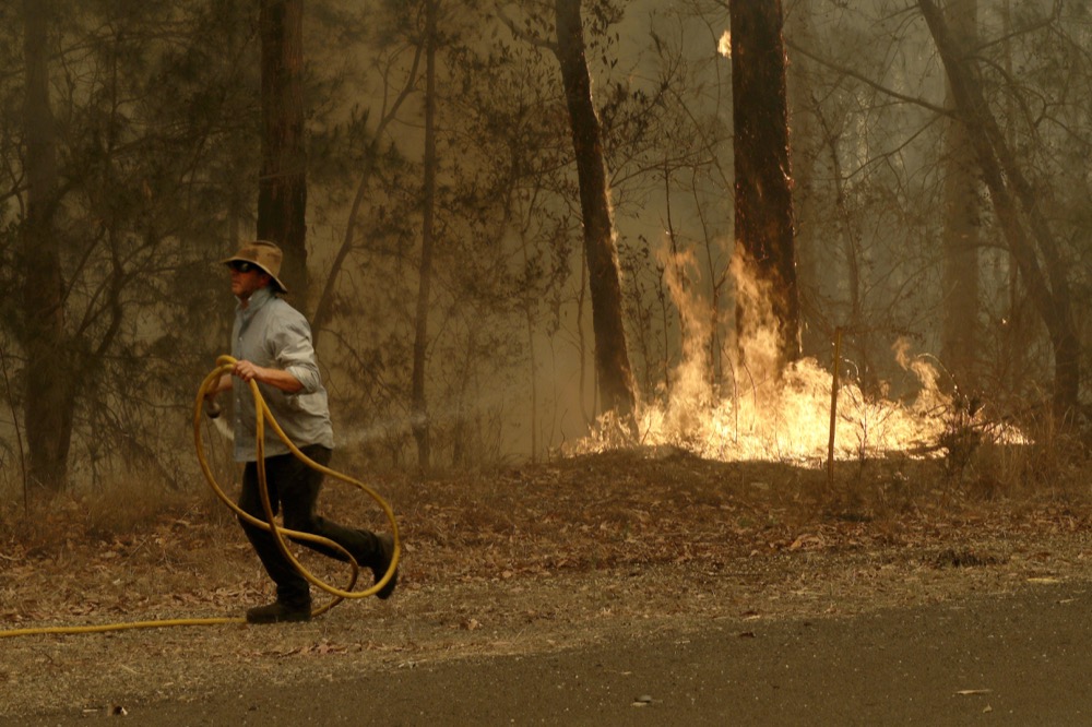 A man runs back to his truck after trying to quench a fire near Moruya, Australia, Saturday, Jan. 4, 2020. Australia's Prime Minister Scott Morrison called up about 3,000 reservists as the threat of wildfires escalated Saturday in at least three states with two more deaths, and strong winds and high temperatures were forecast to bring flames to populated areas including the suburbs of Sydney. (AP Photo/Rick Rycroft)