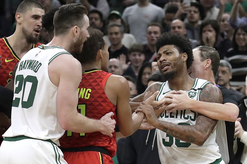 Boston Celtics guard Marcus Smart, right, is held back by a referee as Celtics forward Gordon Hayward (20) holds Atlanta Hawks guard Trae Young (11) during a scuffle in the last seconds of Friday night's game in Boston. The Celtics won 109-106. / AP photo by Elise Amendola