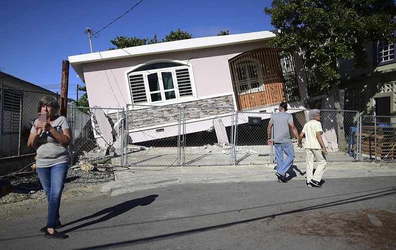 Residents survey damage where a home partially collapsed after an earthquake hit Guanica, Puerto Rico, Monday, Jan. 6, 2020. A 5.8-magnitude quake hit Puerto Rico before dawn Monday, unleashing small landslides, causing power outages and severely cracking some homes. There were no immediate reports of casualties. (AP Photo/Carlos Giusti)