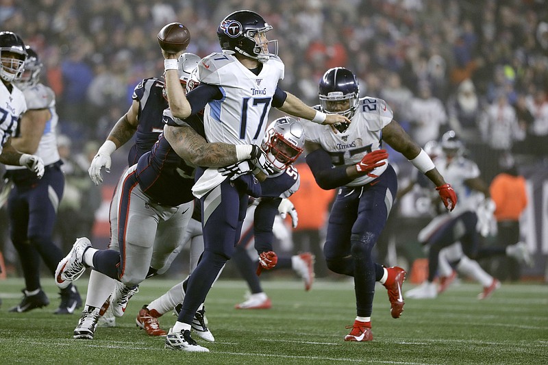 Tennessee Titans quarterback Ryan Tannehill passes while in the grasp of New England Patriots defensive tackle Lawrence Guy in the second half of an NFL wild-card playoff football game, Saturday, Jan. 4, 2020, in Foxborough, Mass. (AP Photo/Steven Senne)