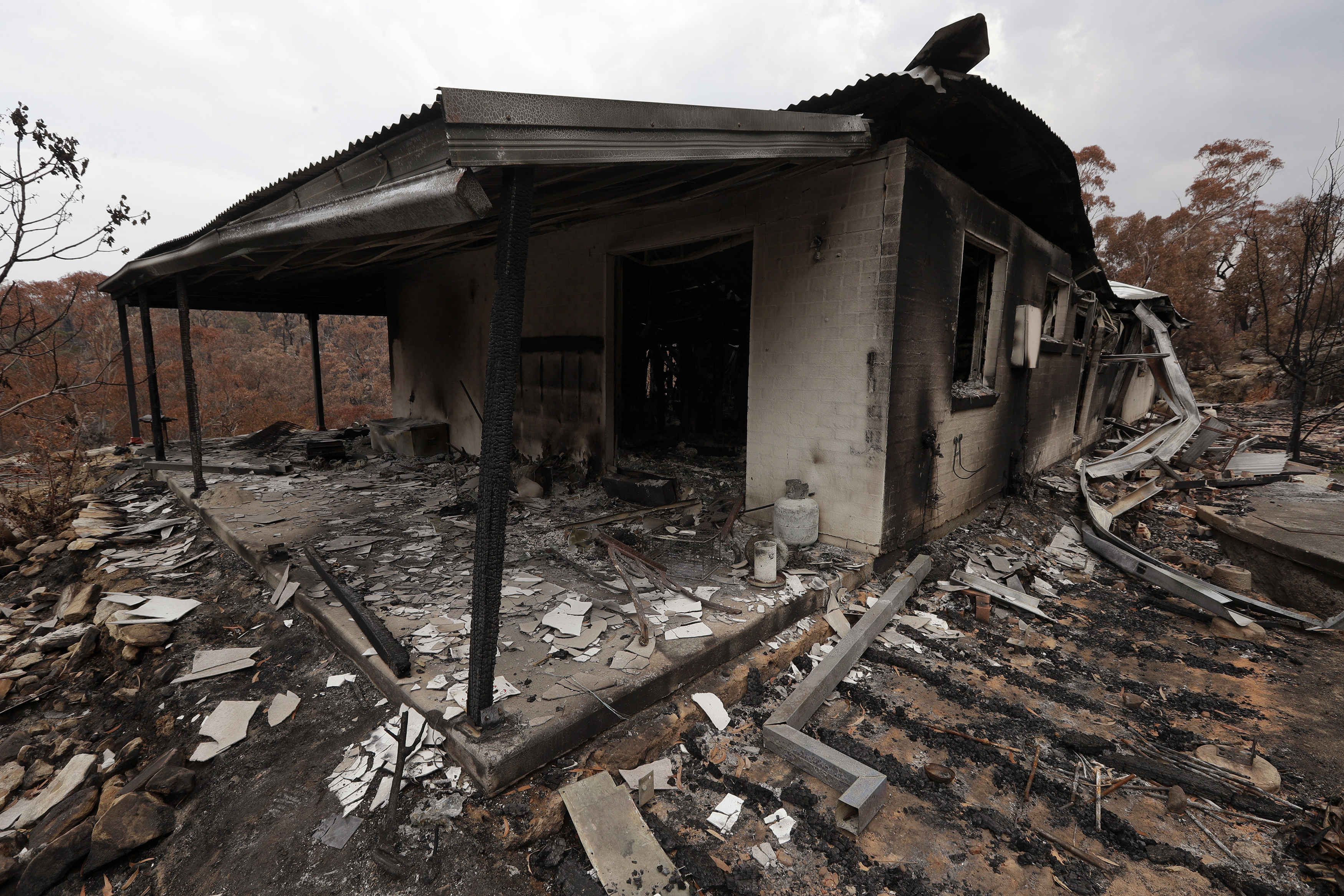 The home of Justin Kam and Helena Wong barely stands after a fire destroyed the house at Balmoral, Australia, Tuesday, Jan. 7, 2020. Kam and Wong built their home with quarter-inch thick reinforced glass, steel framing and rock surrounds to protect them from Australia's notorious wildfires. But as they stayed home with their son and battled flames that soared as high as a 15-story building, they realised they were in mortal danger. (AP Photo/Rick Rycroft)