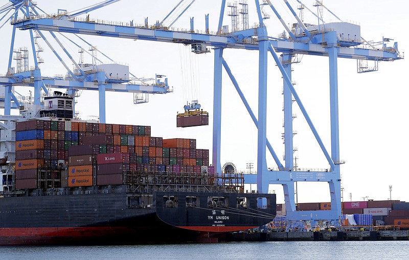 In this Nov. 4, 2019, file photo cargo cranes are used to take containers off of a Yang Ming Marine Transport Corporation boat at the Port of Tacoma in Tacoma, Wash. The Commerce Department said Tuesday, Jan. 7, 2020, that the U.S. trade deficit fell in November to the lowest level in more than three years as U.S. exports rose while imports declined, putting the country on track to see the first annual decline in the trade deficit in six years. (AP Photo/Ted S. Warren, File)