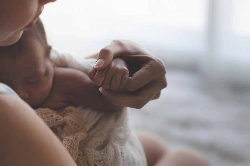Mother holding hand of newborn baby. Mother, new moms and newborn tile. Getty Images/iStockphoto/x-reflexnaja
