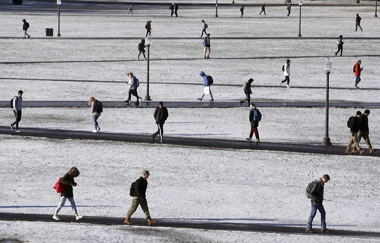 In this Dec. 11, 2019, file photo Virginia Tech students walk across the Drillfield in the snow in Blacksburg Va. Income-driven repayment plans help more than 8 million federal student loan borrowers afford their monthly payments. But these borrowers can still run into trouble if they don't update, or recertify, their income information on time annually. (Matt Gentry/The Roanoke Times via AP, File)