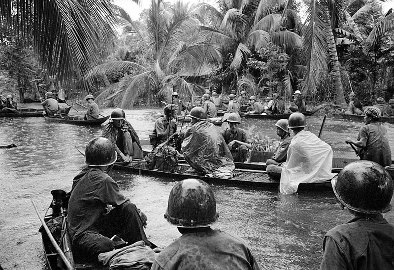 In a sudden monsoon rain, part of a company of about 130 South Vietnamese regional soldiers moves downriver in sampans during a dawn attack against a Viet Cong camp in the flooded Mekong Delta, about 13 miles northeast of Cantho, on Jan. 10, 1966. A handful of guerrillas were reported killed or wounded. (AP Photo/Henri Huet)