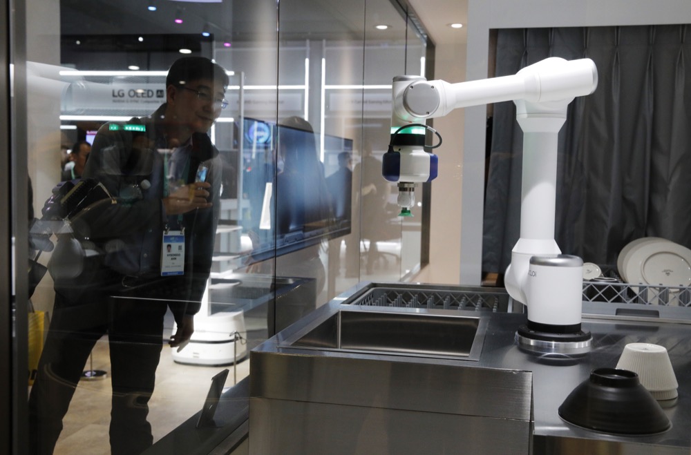 An attendee looks at an LG CLOi CoBot configured to wash dishes in a mock restaurant setting at the LG booth during the CES tech show, Tuesday, Jan. 7, 2020, in Las Vegas. (AP Photo/John Locher)
