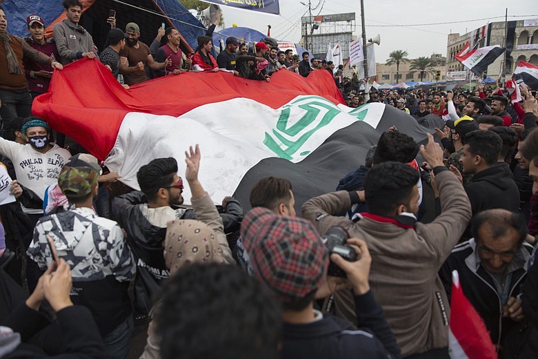 Anti government protesters carry a big Iraqi flag and chant anti Iran and anti U.S. slogans during the ongoing protests in Tahrir square, Baghdad, Iraq, Friday, Jan. 10, 2020. (AP Photo/Nasser Nasser)