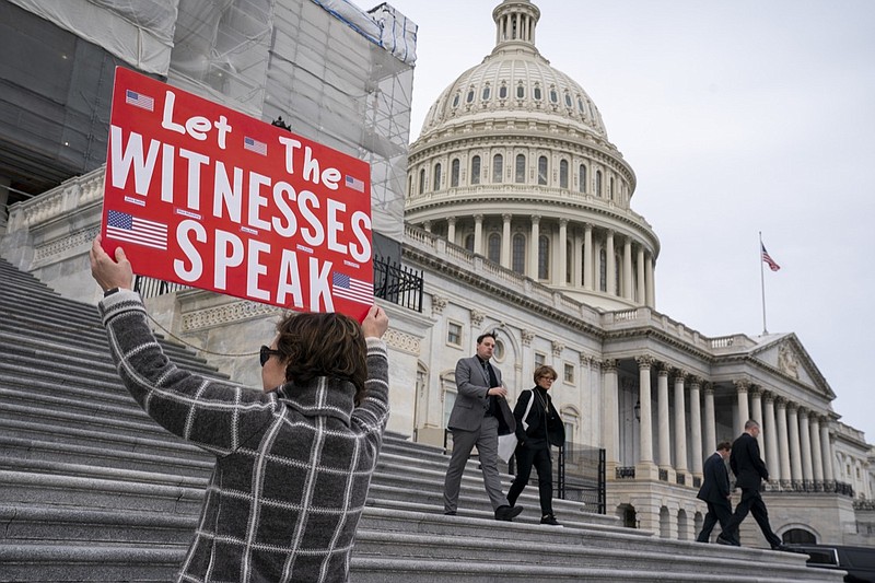 Laura Albinson of Pasadena, Md., displays a message for members of the House as they leave the Capitol in Washington, Friday, Jan. 10, 2020. House Speaker Nancy Pelosi said Friday the House will take steps next week to sent articles of impeachment to the Senate for President Donald Trump's Senate trial. (AP Photo/J. Scott Applewhite)