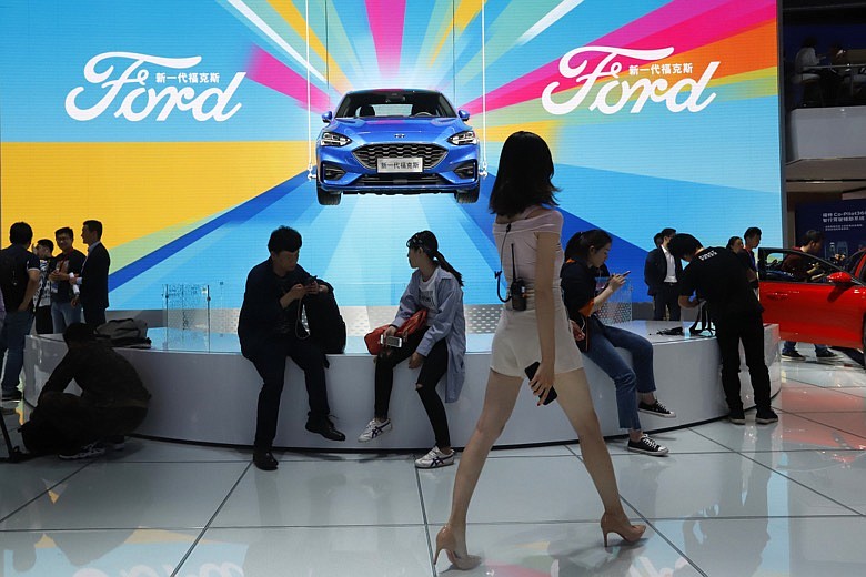In this April 25, 2018, file photo, attendees visit the Ford booth during Auto China 2018 show held in Beijing, China. China's government says it will postpone planned punitive tariffs on U.S.-made automobiles and other goods following an interim trade deal with Washington.Sunday, Dec. 15, 2019's announcement came after Washington agreed to postpone a planned tariff hike on $160 billion of Chinese goods and to cut in half penalties that already were imposed. (AP Photo/Ng Han Guan, File)