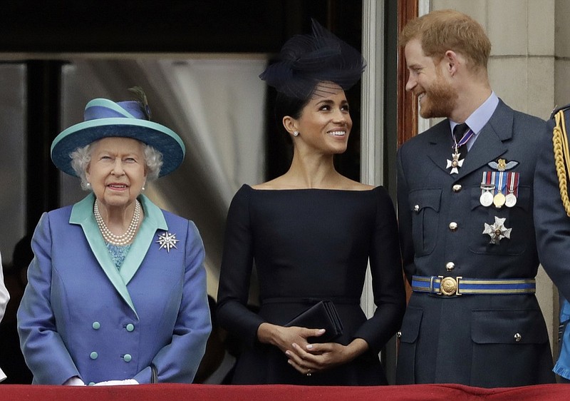 FILE - In this Tuesday, July 10, 2018 file photo Britain's Queen Elizabeth II, and Meghan the Duchess of Sussex and Prince Harry watch a flypast of Royal Air Force aircraft pass over Buckingham Palace in London. As part of a surprise announcement distancing themselves from the British royal family, Prince Harry and his wife Meghan declared they will "work to become financially independent" _ a move that has not been clearly spelled out and could be fraught with obstacles. (AP Photo/Matt Dunham, File)