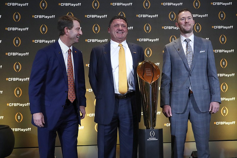 Clemson head coach Dabo Swinney, left, jokes with LSU head coach Ed Orgeron and Oklahoma head coach Lincoln Riley, right, as they pose with the College Football Championship trophy during a news conference ahead for the College Football playoffs Thursday, Dec. 12, 2019, in Atlanta. Ryan Day of Ohio State was unable to attend. (AP Photo/John Bazemore)