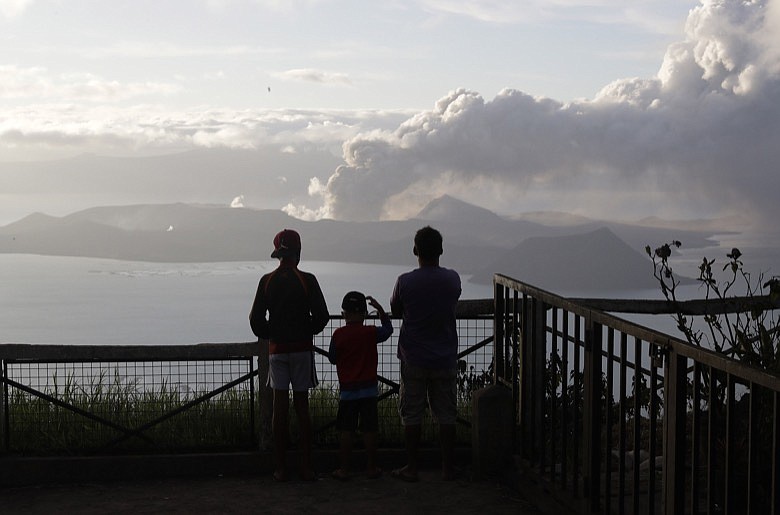 People watch from Tagaytay, Cavite province, south of Manila, as Taal Volcano continues to spew ash on Tuesday, Jan. 14, 2020. Thousands of people fled the area through heavy ash as experts warned that the eruption could get worse and plans were being made to evacuate more.(AP Photo/Aaron Favila)