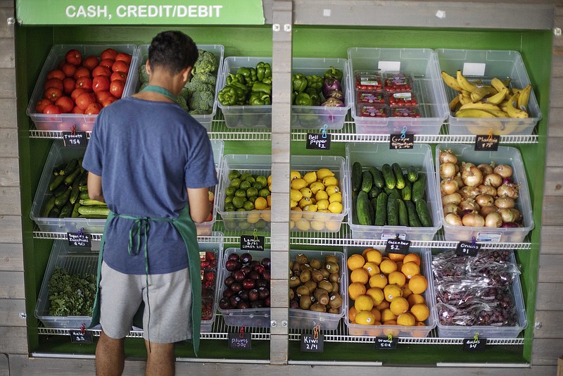 FILE - In this Aug. 21, 2019, file photo a worker stocks a produce stand at a metro station in Atlanta. Throwing away food is throwing away money. And with most wasted food winding up in landfills, it's not great for the environment, either. (AP Photo/David Goldman, File)