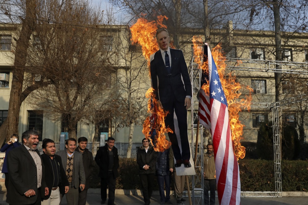 Pro-government protesters set fire to the U.S. and British flags with a life size cut out of Britain’s ambassador to Tehran Rob Macaire in a gathering to commemorate the late Iranian Gen. Qassem Soleimani, who was killed in Iraq in a U.S. drone attack on Jan. 3, and victims of the last week’s Ukrainian plane crash outside Tehran, at the Tehran University campus in Tehran, Iran, Tuesday, Jan. 14, 2020. (AP Photo/Vahid Salemi)