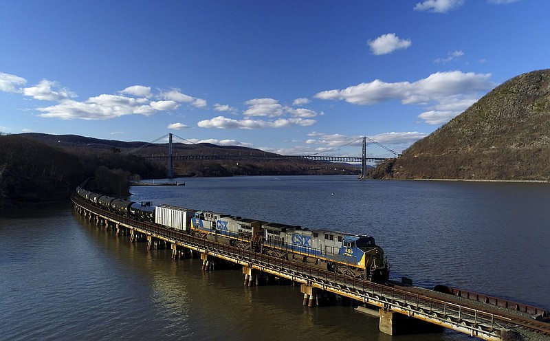 FILE - In this April 26, 2018, file photo a CSX Transportation locomotive pulls a train of tank cars across a bridge on the Hudson River along the edge of Bear Mountain State Park near Fort Montgomery, N.Y. This year's scheduled completion of a $15 billion automatic railroad braking system will bolster the industry's argument for eliminating one of the two crew members in most locomotives. But labor groups argue that single-person crews would make trains more accident prone. (AP Photo/Julie Jacobson, File)