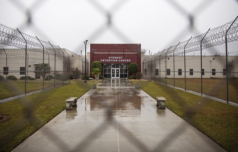 The Stewart Detention Center is seen through the front gate, Friday, Nov. 15, 2019, in Lumpkin, Ga. The rural town is about 140 miles southwest of Atlanta and next to the Georgia-Alabama state line. The town's 1,172 residents are outnumbered by the roughly 1,650 male detainees that U.S. Immigration and Customs Enforcement said were being held in the detention center in late November. (AP Photo/David Goldman)