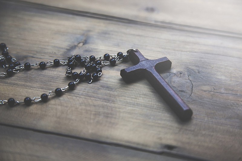 wooden cross on the wooden table background catholic church tile / Getty Images
