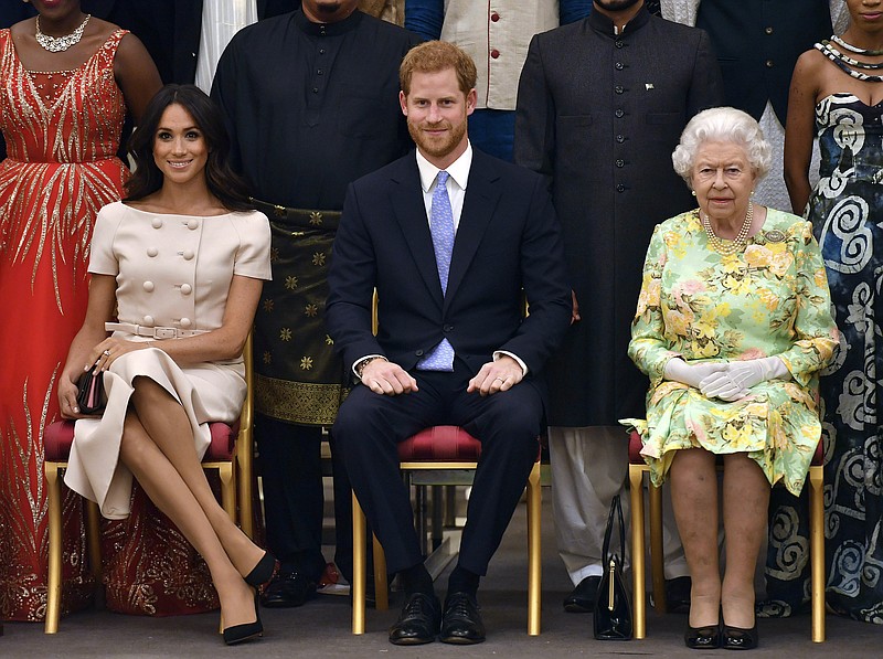FILE - In this Tuesday, June 26, 2018 file photo Britain's Queen Elizabeth, Prince Harry and Meghan, Duchess of Sussex pose for a group photo at the Queen's Young Leaders Awards Ceremony at Buckingham Palace in London. Prince Harry and Meghan Markle are to no longer use their HRH titles and will repay £2.4 million of taxpayer's money spent on renovating their Berkshire home, Buckingham Palace announced Saturday, Jan. 18. 2020. (John Stillwell/Pool Photo via AP, File)

