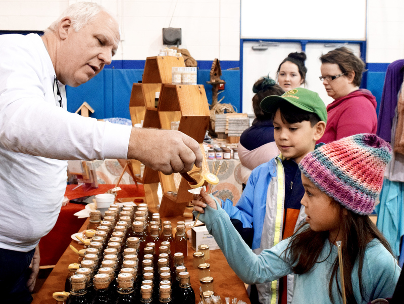Staff Photo by Robin Rudd/ Bee keeper Shannon Baxter gives Ella Cusion a taste of his honey, while Ella's brother looks on at the Birchwood Community Center. The 29th Annual Tennessee Sandhill Crane Festival celebrates the thousands of birds that migrate through or spend the winter on and around the Hiwassee Refuge. The festival, the final day was January 19, 2020, also provides an opportunity to focus on the rich wildlife heritage of the state and the Native American history of the area.