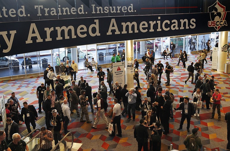 FILE - In this Wednesday, Jan. 24, 2018, file photo, people walk through the hall outside of the SHOT Show gun show in Las Vegas. The gun industry is gathering for its annual conference, in January 2020, amid a host of uncertainty: slumping gun sales, a public increasingly agitating for restrictions on access to firearms and a presidential campaign that threatens gun rights like perhaps no other time in modern American history. (AP Photo/John Locher, File)