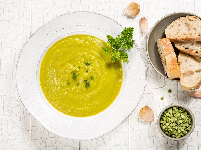 Close up of homemade split pea soup with garlic, bread and parsley for garnish. / Getty Images/iStockphoto/juliannafunk