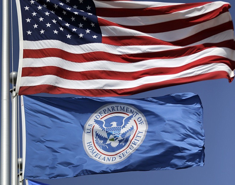 In this July 31, 2014 file photo, the U.S. and U.S. Department of Homeland Security flags fly in Karnes City, Texas. The Trump administration pledged Friday to step up efforts against the vast amounts of counterfeit clothing, medicine and other goods that have flooded into the U.S. with the rise in e-commerce. The move was announced Friday by Chad Wolf, acting secretary of the Department of Homeland Security. (AP Photo/Eric Gay)